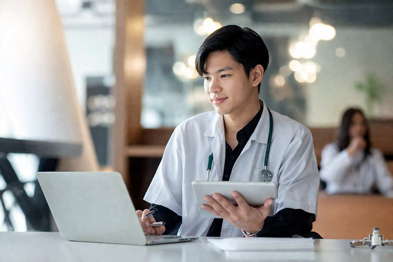 Doctor using laptop and tablet for MRCOG course preparation and online medical learning
